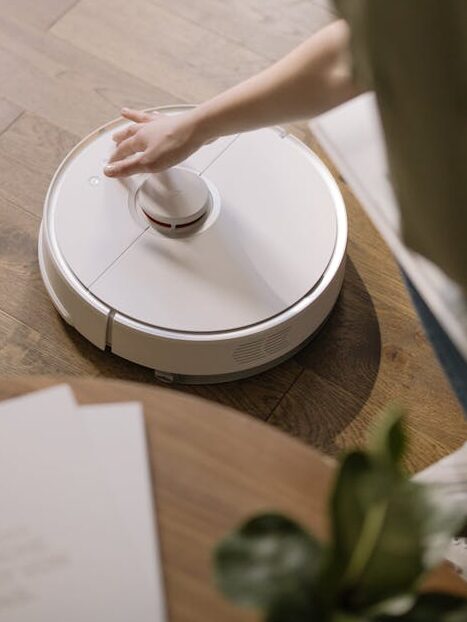 pexels-photo-4107242 A woman interacts with a robotic vacuum on a wooden floor, showcasing smart home technology.